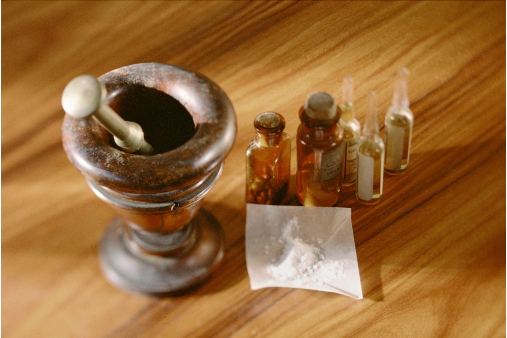 Pharmaceutical bottles, pestle and mortar, and pills, depicting drug scheduling, as explained by Avenues Recovery.