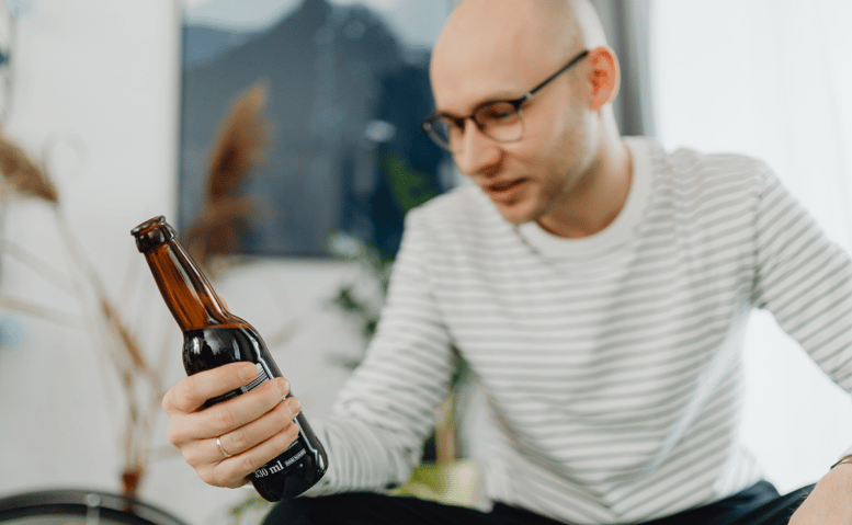 Habit or Addiction? Man Looking At Beer Unsure
