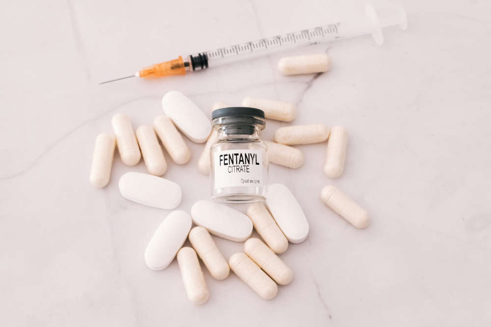 Fentanyl bottle surrounded by pills and syringe. Fentanyl Baby Syndrome results from fentanyl use in pregnancy
